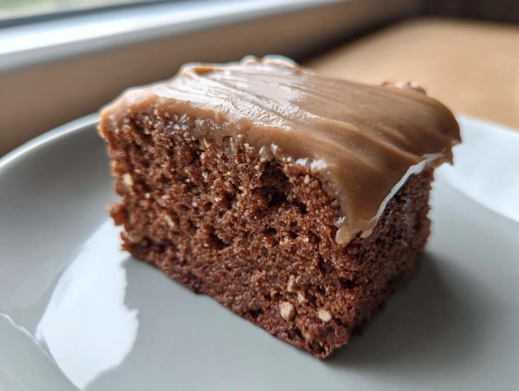 A single square slice of Frosted Coffee Brownies on a light gray plate, showing the rich brown cake and smooth coffee frosting.