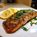 A perfectly cooked best air fryer salmon fillets on a white plate, garnished with fresh parsley and lemon slices.