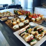 An assortment of bridal shower food, including sandwiches, fruit skewers, and cupcakes, beautifully arranged on platters.