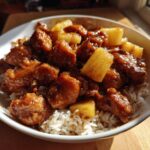 A bowl of chicken pineapple recipe served over white rice, showcasing the sweet and savory dish.