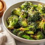 Close-up of a bowl filled with roasted Garlic Parmesan Broccoli, sprinkled with parmesan cheese.