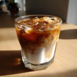 A refreshing Iced Caramel Macchiato in a glass, showcasing layers of milk, coffee, caramel, and ice.