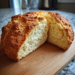 Close-up of sliced Irish food: soda bread on a wooden cutting board, showcasing its golden crust and soft interior.