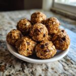 A bowl full of homemade oatmeal protein balls with visible oats and chocolate chips.