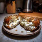 A sliced protein bagel with greek yogurt filling, showing the creamy texture and everything bagel seasoning.