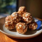 A stack of homemade protein balls no bake, coated in oats, on a rustic plate.