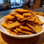 A white bowl filled with a stack of homemade sourdough cheez its, ready to eat.