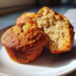 Close-up of sourdough discard banana muffins, one cut in half to show the texture.