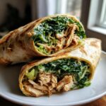 A delicious chicken caesar wrap with rotisserie chicken, lettuce, and creamy dressing, cut in half to show the filling.