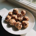 A plate of homemade rolled oats protein balls no peanut butter, displayed near a window.