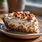 A slice of Texas Trash Pie Southern Living, topped with whipped cream, pecans, and chocolate chunks.