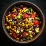 Overhead shot of a colorful bowl of 15-Minute Cowboy Caviar with beans, corn, tomatoes, and avocado.