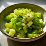 Close-up of 15-Minute Crisp Celery Salad in a bowl, garnished with herbs and pepper.