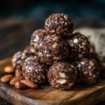 A stack of delicious 5-Minute No-Bake Protein Balls on a wooden board with almonds.