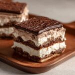 A delicious slice of 5-Star Chocolate Lasagna with layers of chocolate cake and creamy filling on a wooden tray.
