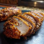 Sliced Air Fryer Chicken Breast with a golden-brown crust and juicy interior, seasoned with herbs and spices.