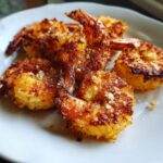 Close-up of golden brown Air Fryer Frozen Shrimp on a white plate, showcasing the crispy breading.