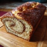 Close-up of a loaf of Amish Cinnamon Bread, showcasing the cinnamon swirl and golden-brown crust.