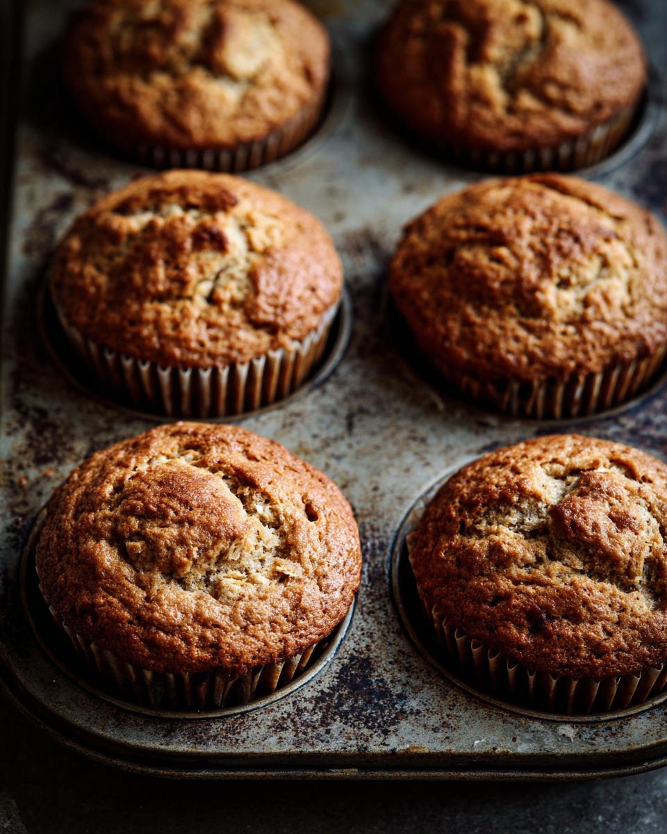 Close-up of freshly baked One-Bowl Ultra Moist Banana Oatmeal Muffins in a muffin tin, ready to eat.