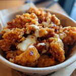 Bowl of crispy Bang Bang Chicken drizzled with creamy sauce, ready to eat.