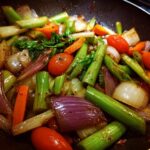 Close-up of a vibrant Broccoli Mushroom Stir Fry with broccoli, mushrooms, onions, carrots, and tomatoes in a pan.