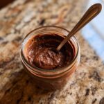 Overhead view of Brownie Batter Chocolate Overnight Oats in a glass jar with a spoon.