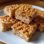 A stack of homemade Ultimate Chewy Peanut Butter Rice Krispie Treats on a white plate.