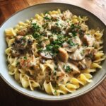 A bowl of creamy Chicken Stroganoff with egg noodles, mushrooms, and parsley garnish.