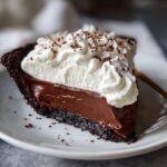 A slice of The Best Classic Chocolate Cream Pie with whipped cream and chocolate shavings on a white plate.