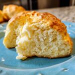 A close-up of a piece of cloud bread on a blue plate, showcasing its light and airy texture.