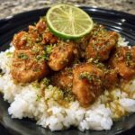 A serving of Coconut Lime Chicken on rice, garnished with lime zest and a lime slice.