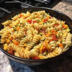 Bowl of vibrant Cold Pasta Salad featuring rotini pasta, colorful vegetables, and fresh herbs.