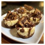 Irresistible No-Bake Cookie Butter Cheesecake Cups drizzled with chocolate and topped with cookie pieces.