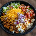 Overhead shot of a Cottage Cheese Taco Bowl with ground meat, cheese, lettuce, tomatoes, and red onions.