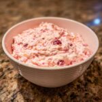 A bowl of The BEST 15-Min Cranberry Fluff Salad, a pink dessert salad with cranberries and other fruits.