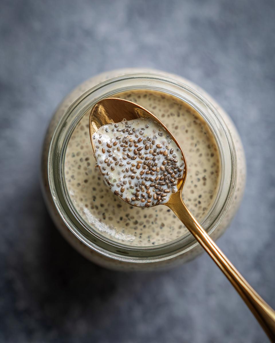 Overhead shot of creamy chia pudding base in a jar, with a spoonful held above. 