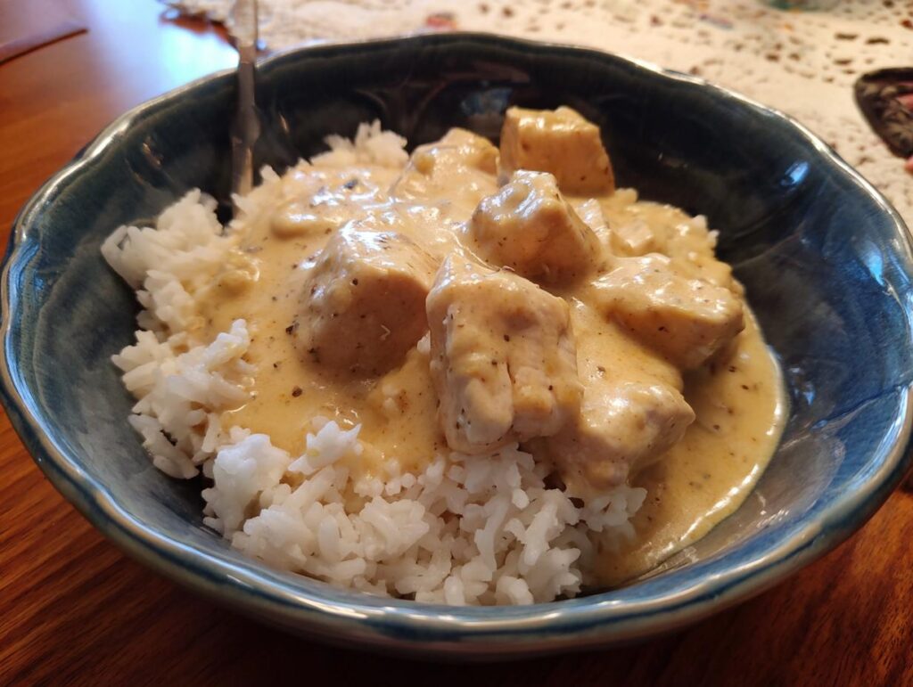 A bowl of Creamy Crockpot Chicken and Rice, featuring tender chicken pieces in a creamy sauce over white rice.