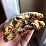 A halved Crumbl Chocolate Chip Cookie shows the gooey chocolate inside.