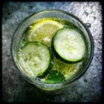 Overhead view of Cucumber Mint Lemonade in a glass with cucumber slices, lemon, and mint.