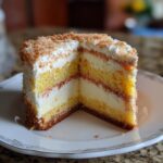 A slice of Decadent Italian Love Cake showing layers of cake, cream, and a crumb topping.