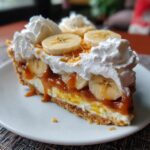 A slice of Easy No-Bake Banoffee Pie, topped with bananas, whipped cream, and caramel.