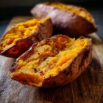 Close-up of halved The ULTIMATE Fluffy Baked Sweet Potato on a wooden board, showing the fluffy interior.