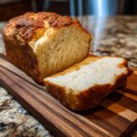 A loaf of The Ultimate Fluffy Condensed Milk Bread with a slice cut, showing the soft texture.