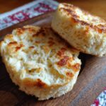 Two halves of Ultimate Fluffy Homemade English Muffins on a wooden board, showing the texture and golden-brown toasting.