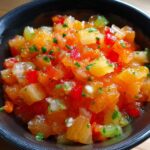 A bowl of The Fresh Peach Salsa, featuring diced peaches, red peppers, green onions, and herbs.