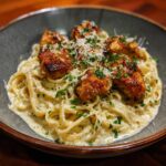 A bowl of Garlic Butter Chicken Bites Creamy Parmesan Pasta, garnished with parsley and parmesan.