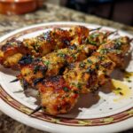 Close-up of Garlic Parmesan Chicken Skewers on a plate, showing the golden-brown chicken and herb garnish.