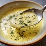 Close-up of 5 Minute Garlic Parmesan Cream Sauce on a spoon, garnished with herbs and spices.