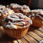 Close-up of Golden Swirl Cinnamon Roll Cupcakes, a cozy treat with icing on a wire rack.