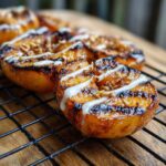 Close-up of grilled peaches honey yogurt dessert, drizzled with yogurt and topped with nuts on a cooling rack.